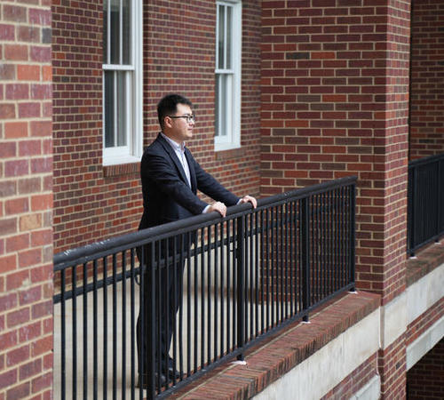 Edward Wang looking over railing into courtyard. 