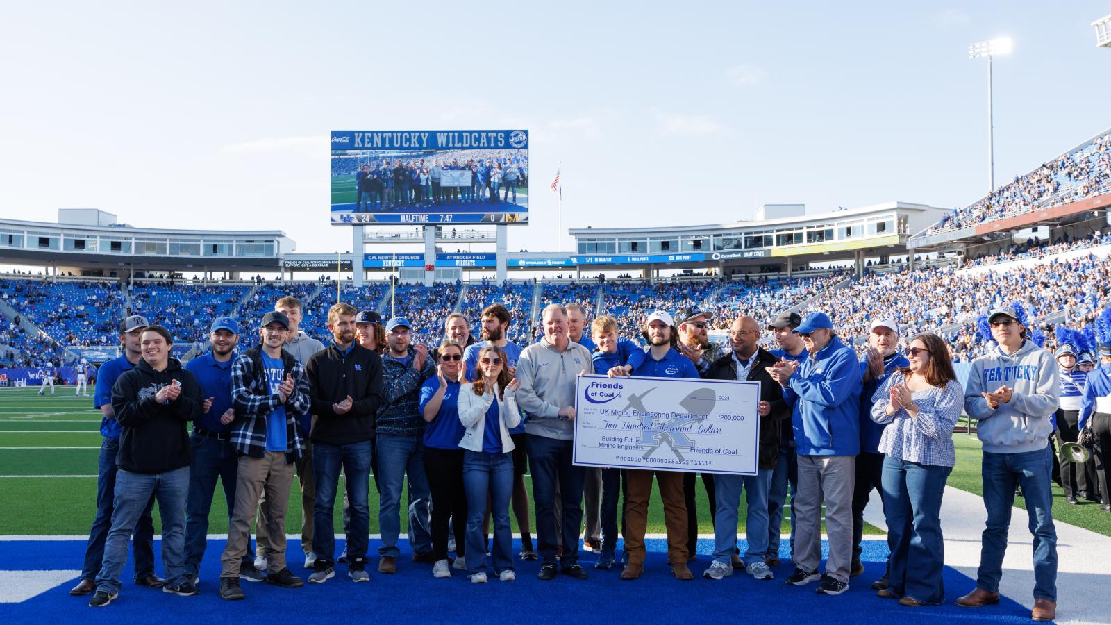 Group of People on football field with big check