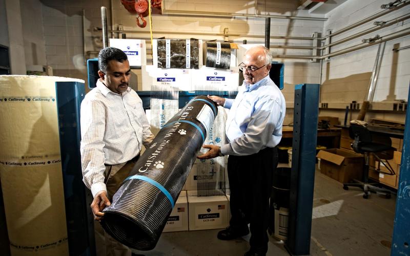 Abheetha Peiris (left) and Issam Harik (right) holding a roll of CatStrong carbon-fiber panels